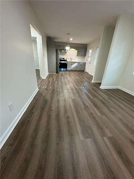 unfurnished living room featuring baseboards, a sink, and dark wood-type flooring