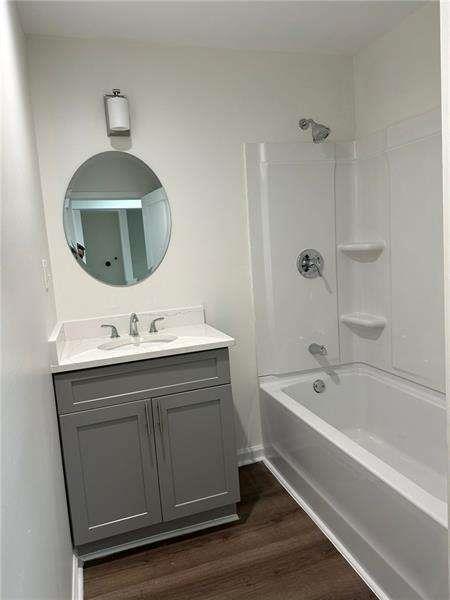 bathroom with vanity, wood finished floors, and tub / shower combination