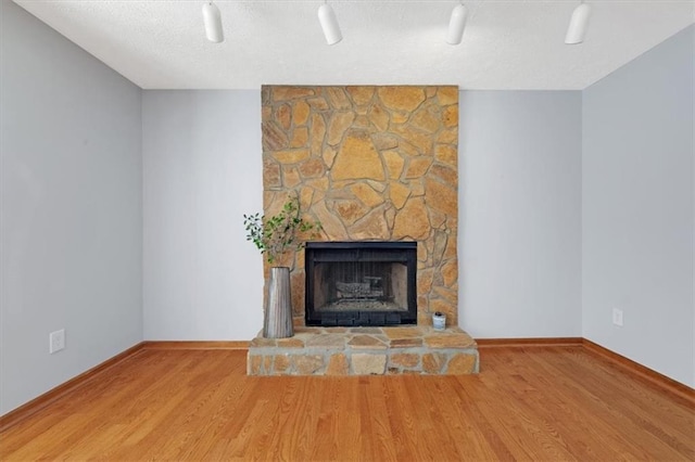 unfurnished living room featuring a stone fireplace and hardwood / wood-style floors