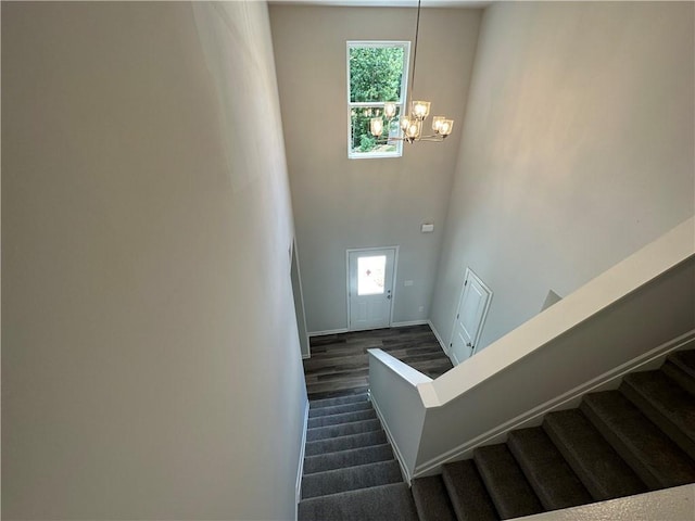 stairs with a high ceiling, a wealth of natural light, and a chandelier