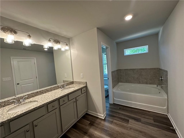 bathroom featuring a tub, wood-type flooring, toilet, and vanity