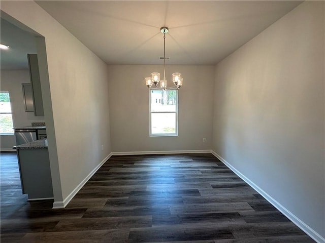 empty room with dark hardwood / wood-style floors and a notable chandelier