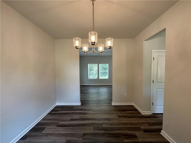 unfurnished dining area featuring dark wood-type flooring and an inviting chandelier