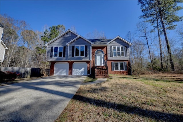 split foyer home with brick siding, a front yard, an attached garage, and driveway