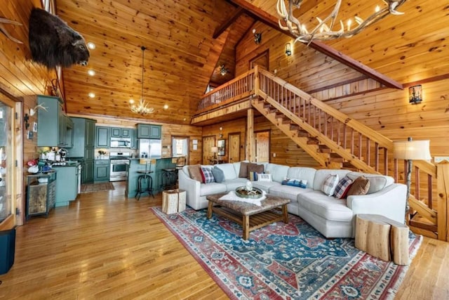 living area with light wood-type flooring, high vaulted ceiling, wooden walls, an inviting chandelier, and wood ceiling