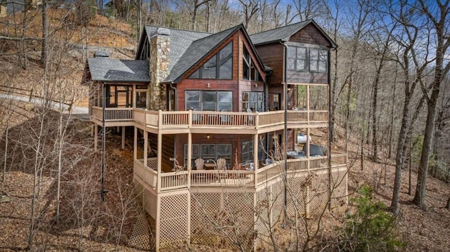 back of property with a shingled roof and a deck