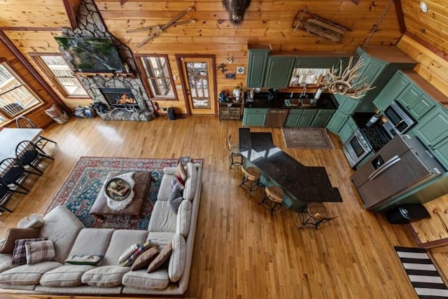 living room featuring a stone fireplace, lofted ceiling, wood finished floors, and a wealth of natural light