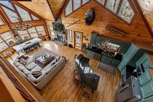 living room featuring high vaulted ceiling, wood finished floors, wooden walls, an inviting chandelier, and wooden ceiling