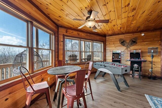 interior space featuring wood walls, wooden ceiling, a ceiling fan, and wood finished floors