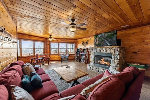 living area with wooden walls, wooden ceiling, a fireplace, and wood finished floors