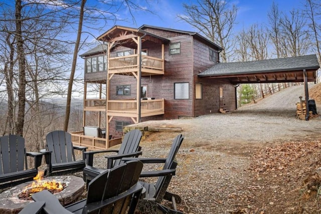 exterior space with a balcony, dirt driveway, and an outdoor fire pit