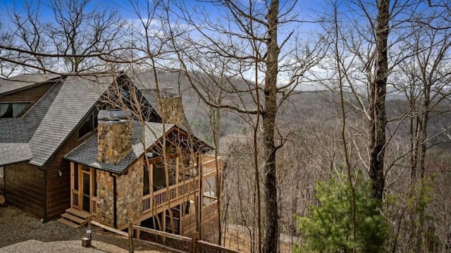 exterior space with stone siding and a shingled roof