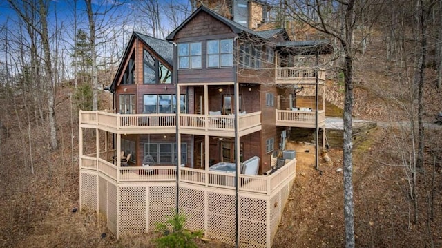 rear view of house featuring central air condition unit, a chimney, and a balcony