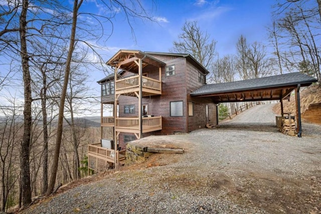 view of front of home featuring gravel driveway, a carport, and a balcony