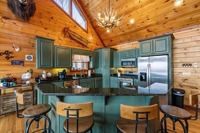 kitchen with a sink, stainless steel appliances, wooden walls, and light wood-style flooring