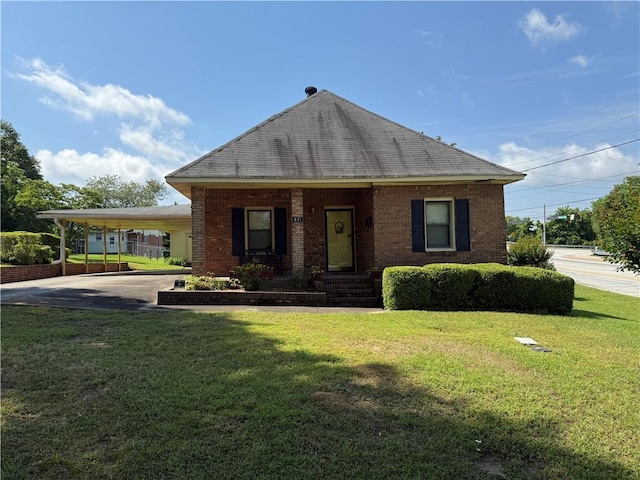 view of front of house with a front lawn, an attached carport, and brick siding