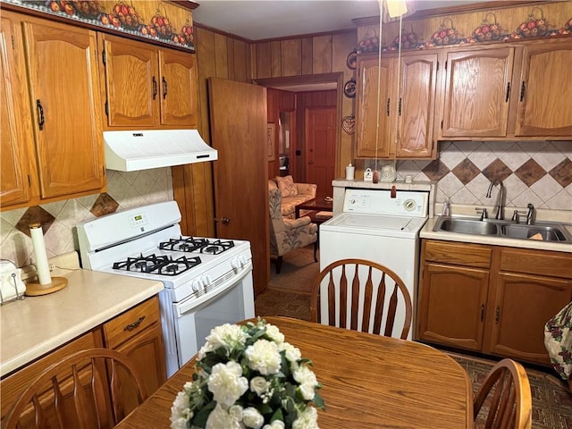kitchen featuring range hood, white range with gas cooktop, a sink, washer / clothes dryer, and decorative backsplash