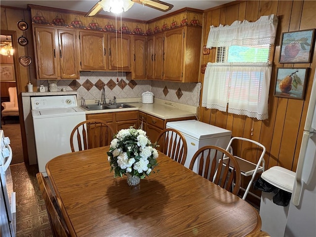 kitchen with washer / clothes dryer, a sink, brown cabinetry, light countertops, and ceiling fan