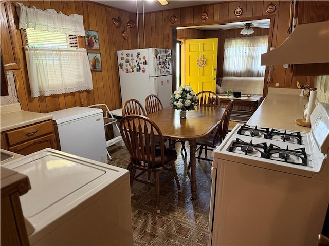 dining area featuring a ceiling fan, wood walls, and washer / dryer
