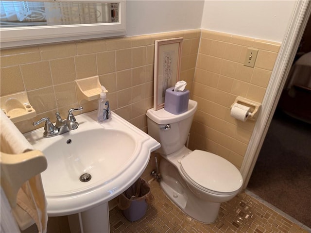 bathroom featuring toilet, tile walls, and wainscoting