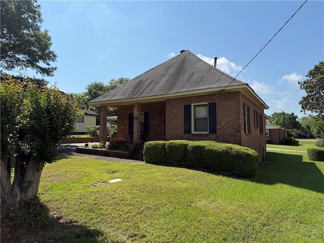 view of side of property featuring a lawn, brick siding, and roof with shingles