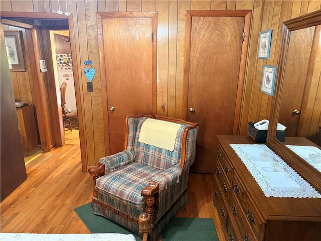 living area featuring light wood-style flooring and wood walls