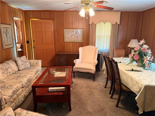living room featuring carpet floors, ceiling fan, wood walls, and ornamental molding