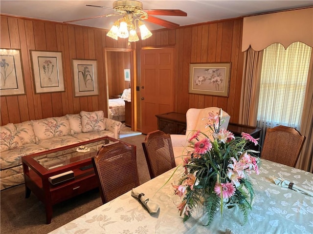 carpeted living room featuring ceiling fan and wooden walls