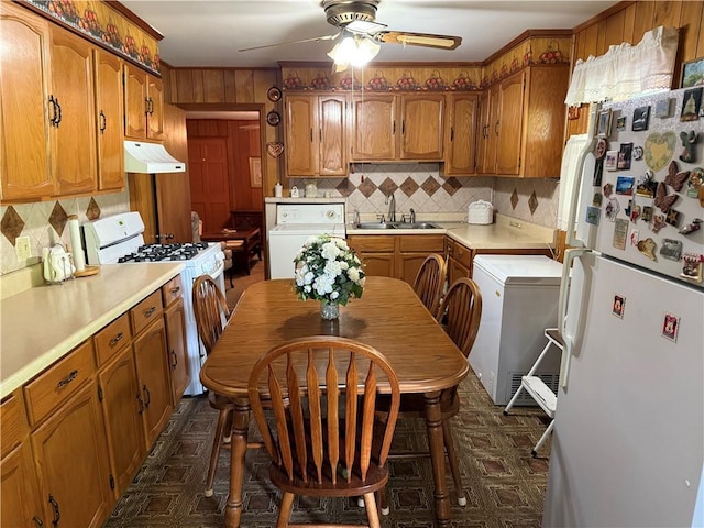 kitchen featuring washer / dryer, white appliances, under cabinet range hood, a sink, and ceiling fan