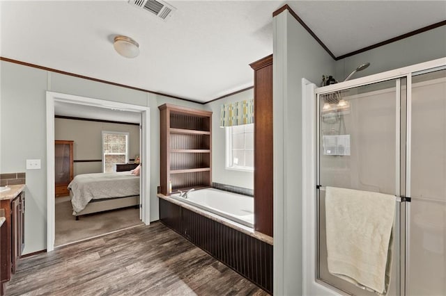 ensuite bathroom with visible vents, ornamental molding, a shower stall, ensuite bath, and wood finished floors