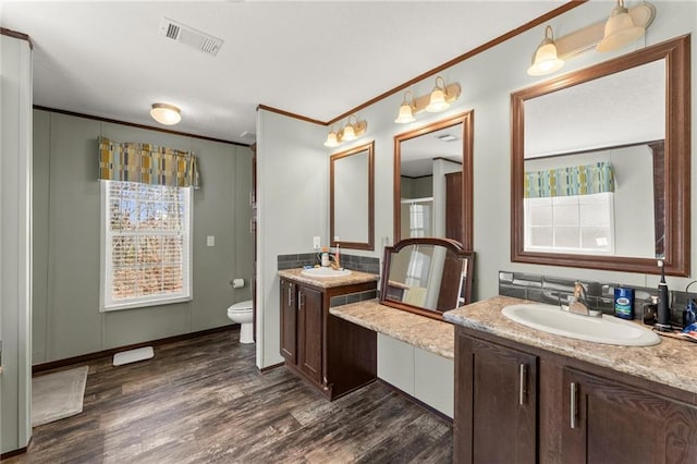 full bath featuring crown molding, visible vents, a sink, and wood finished floors