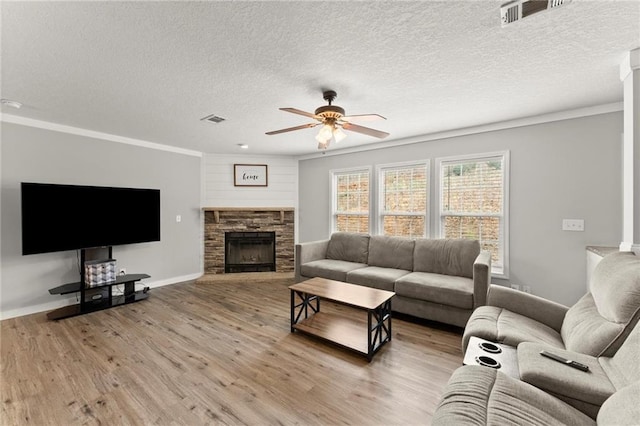 living room with a stone fireplace, wood finished floors, visible vents, baseboards, and a ceiling fan