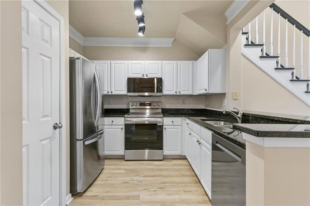 kitchen with white cabinets, decorative backsplash, sink, and stainless steel appliances