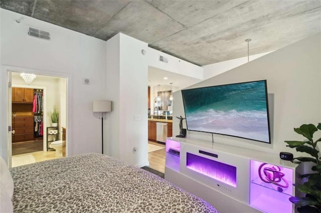 bedroom with light wood-type flooring, ensuite bathroom, a notable chandelier, and sink