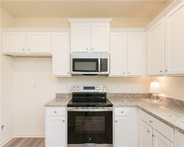 1577 Aiden Way Unit 39, Conyers, GA 30013 - kitchen with appliances with stainless steel finishes, white cabinetry, light stone countertops, baseboards, and light wood-type flooring