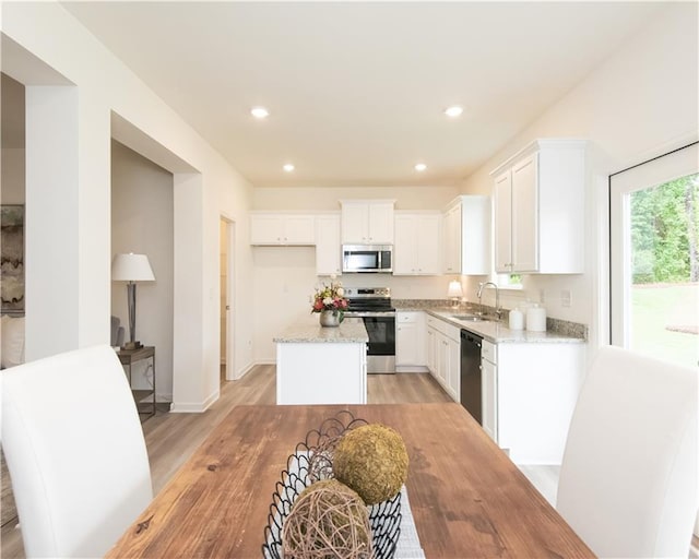 1577 Aiden Way Unit 39, Conyers, GA 30013 - kitchen with stainless steel appliances, light wood-type flooring, a sink, white cabinetry, and a kitchen island
