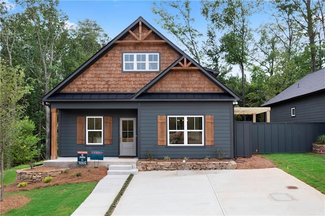 craftsman house featuring a standing seam roof, a patio, fence, a front yard, and metal roof