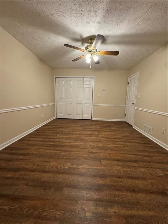 unfurnished bedroom featuring ceiling fan, dark wood-type flooring, a textured ceiling, and a closet