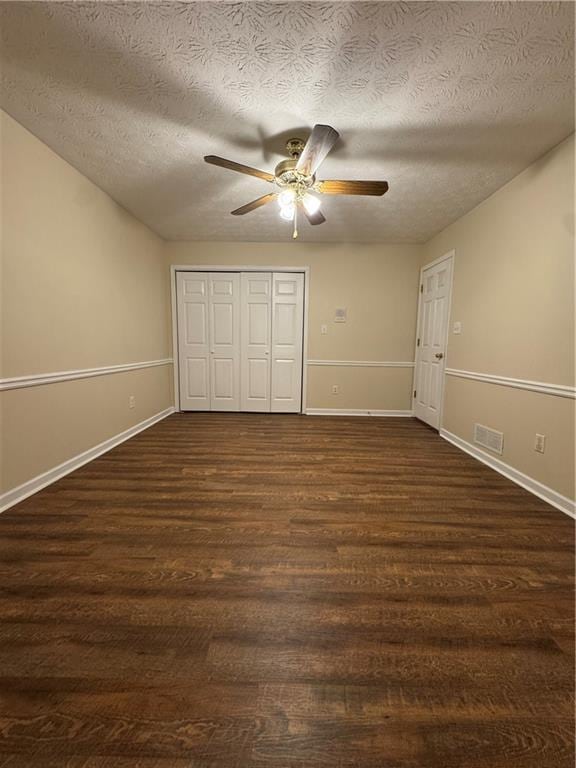 unfurnished bedroom with a textured ceiling, a closet, ceiling fan, and dark hardwood / wood-style flooring