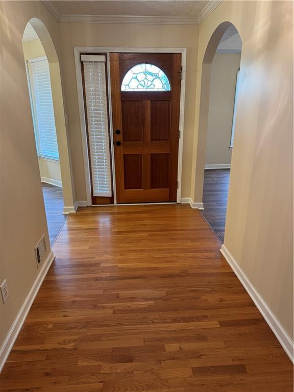 foyer with ornamental molding and dark wood-type flooring