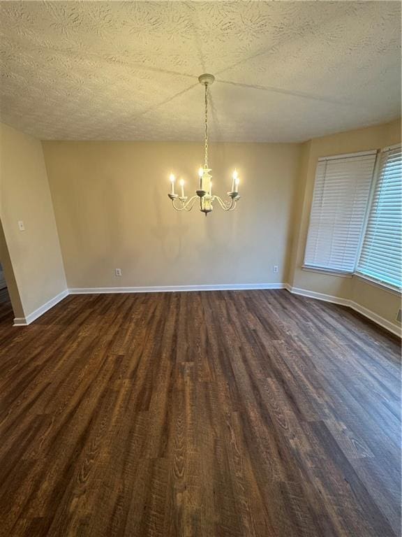 unfurnished dining area with dark hardwood / wood-style floors, a textured ceiling, and a notable chandelier