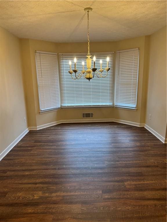 interior space featuring dark wood-type flooring, an inviting chandelier, and a textured ceiling