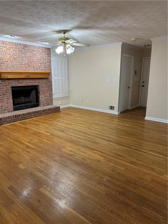 unfurnished living room with hardwood / wood-style flooring, a textured ceiling, ceiling fan, crown molding, and a brick fireplace