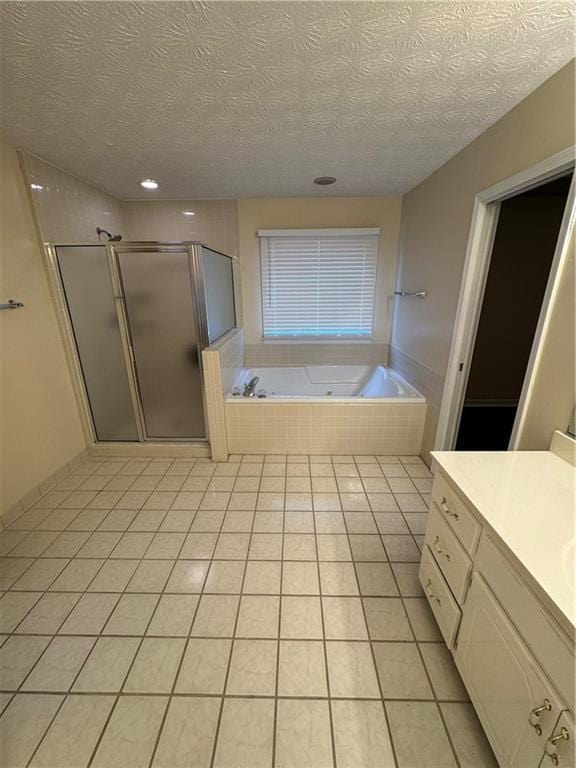 bathroom featuring plus walk in shower, vanity, a textured ceiling, and tile patterned floors