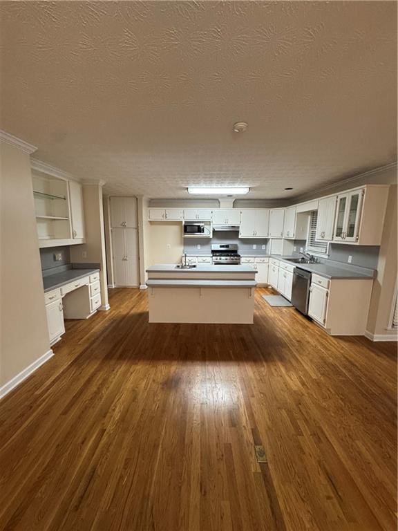 kitchen with appliances with stainless steel finishes, a kitchen island, built in desk, and white cabinets