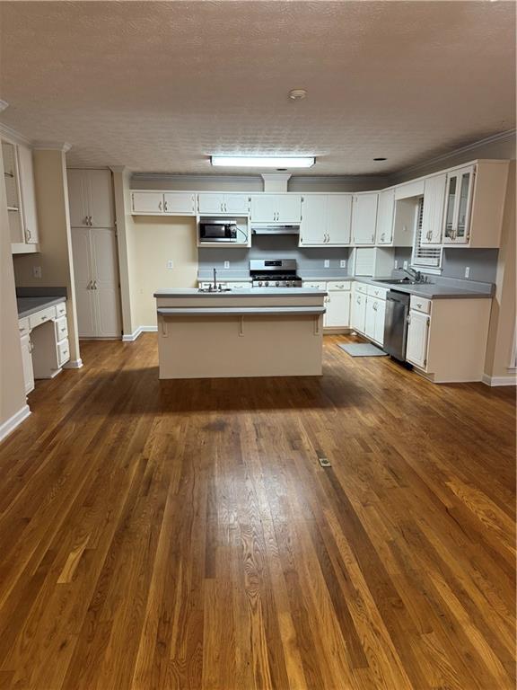 kitchen with appliances with stainless steel finishes, a kitchen island, white cabinetry, and dark hardwood / wood-style floors