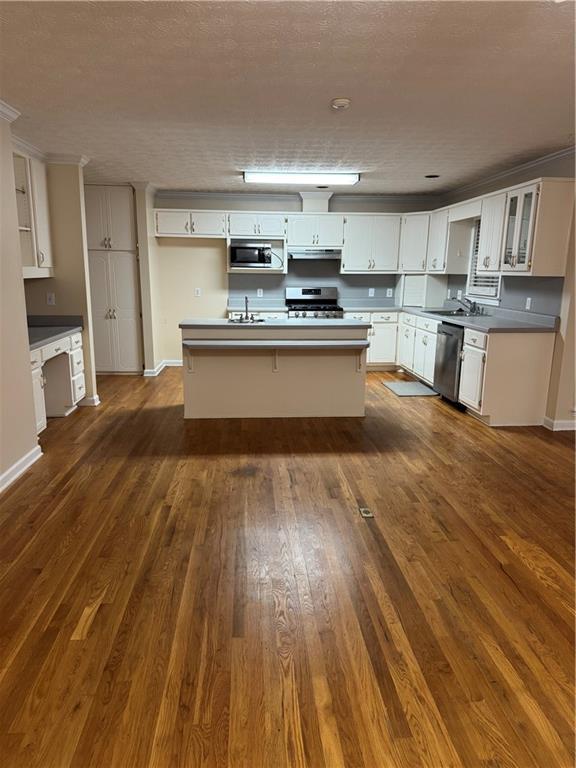 kitchen with sink, a center island, stainless steel appliances, dark hardwood / wood-style flooring, and white cabinets