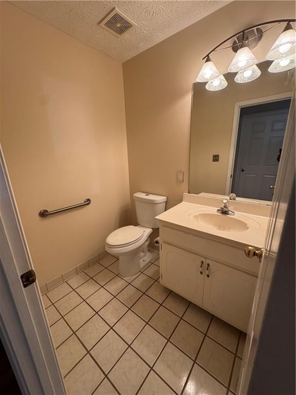 bathroom featuring tile patterned flooring, vanity, toilet, and a textured ceiling