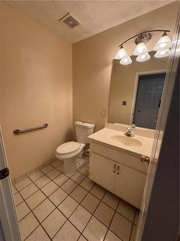 bathroom with a textured ceiling, vanity, toilet, and tile patterned floors