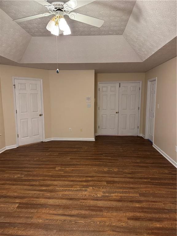 interior space featuring a textured ceiling, vaulted ceiling, and dark hardwood / wood-style flooring